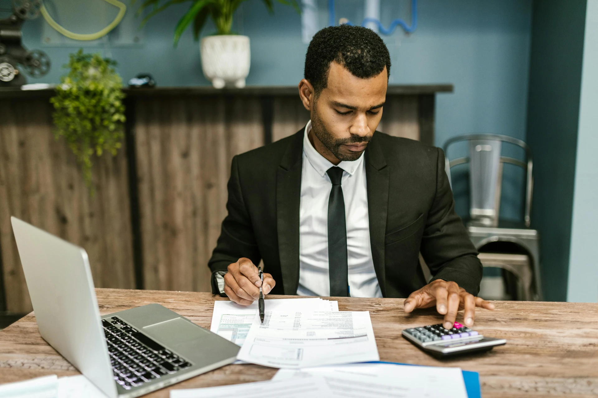 Business professional reviewing financial paperwork with a laptop and calculator.